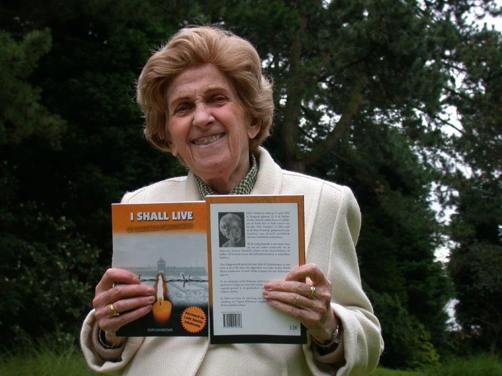 Edith Davidovici holding her book 'I Shall Live' — a radiant smile